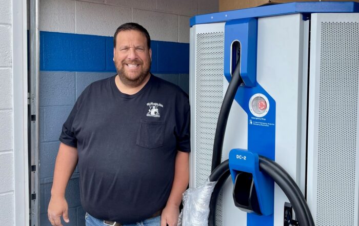 CR Electric owner, Jason Rubin, stands with EV charger to be installed at Greenwood Chevrolet in Austintown